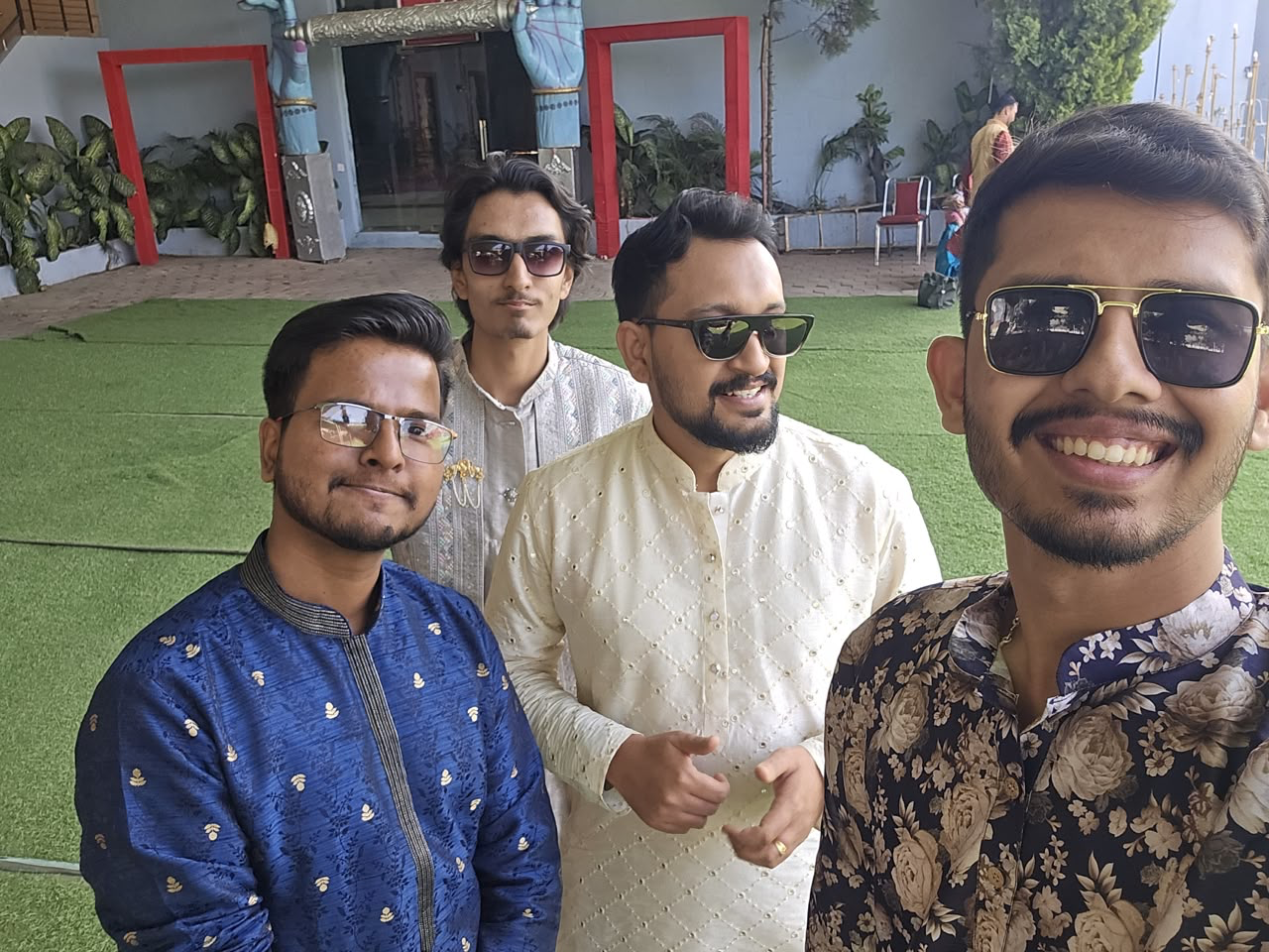 Group selfie of four friends in kurtas at a wedding venue